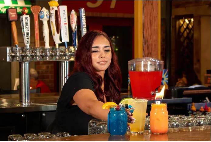 A woman is serving drinks at a bar.