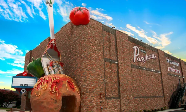 A large tomato is hanging from the side of a building.