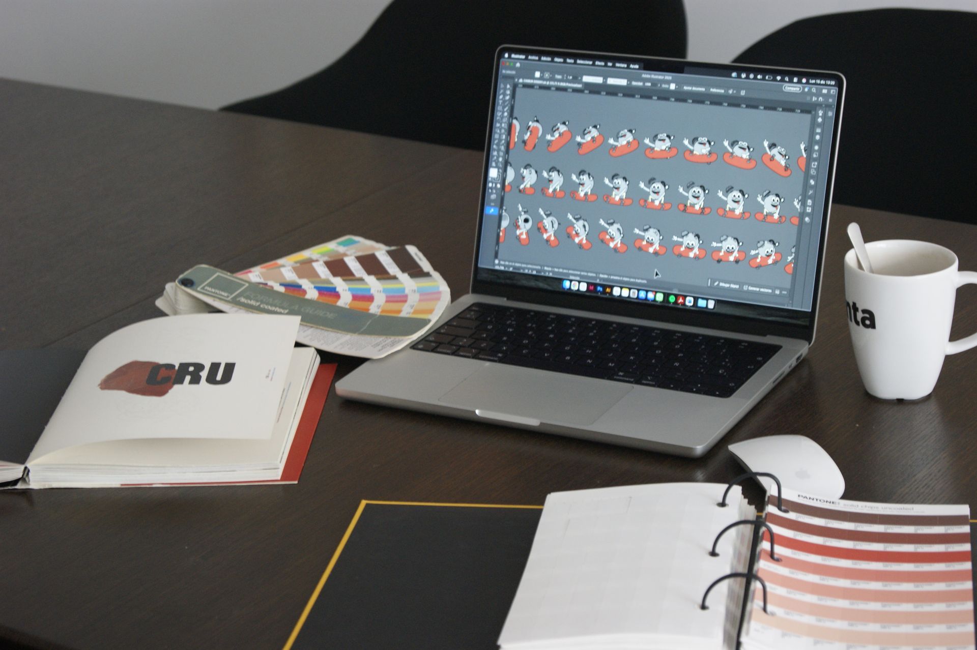 Ordinador portàtil que mostra disseny, mostres de color, tassa sobre taula.