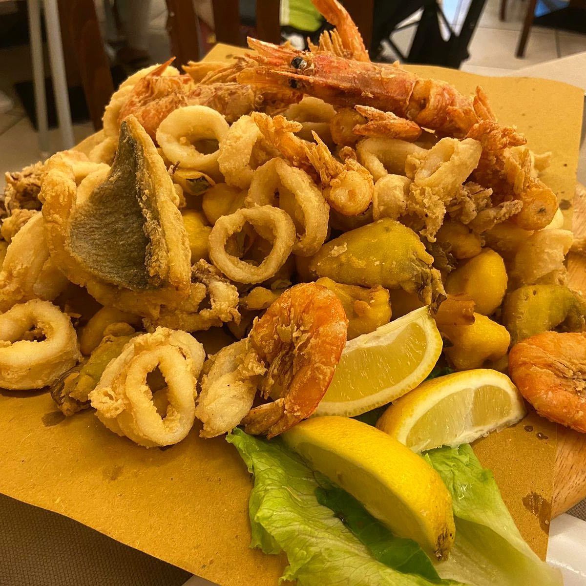 Piatto di frutti di mare fritti con spicchi di limone e lattuga.