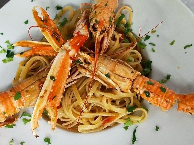 Linguine con scampi cotti, guarnite con prezzemolo.