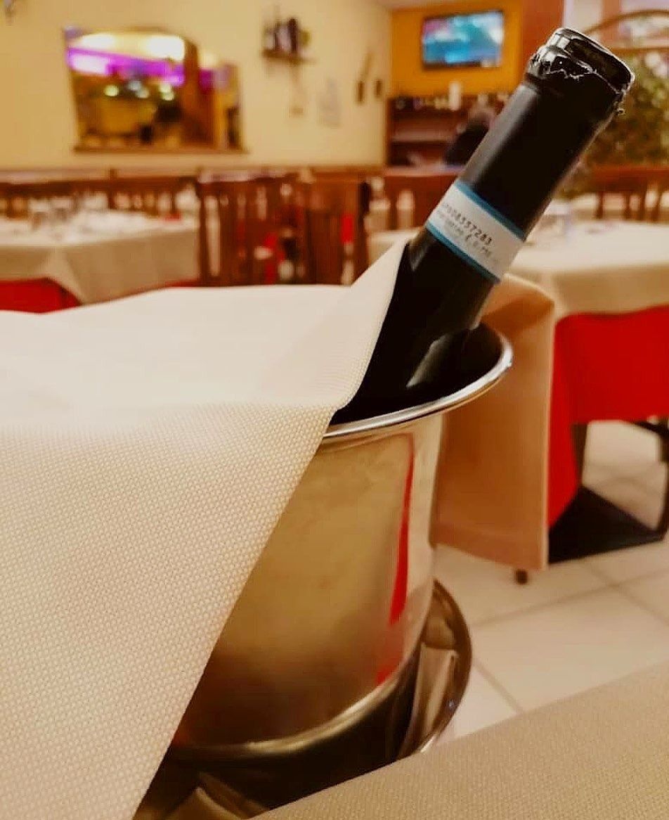Bottiglia di vino in un secchiello del ghiaccio su un tavolo in un ristorante.
