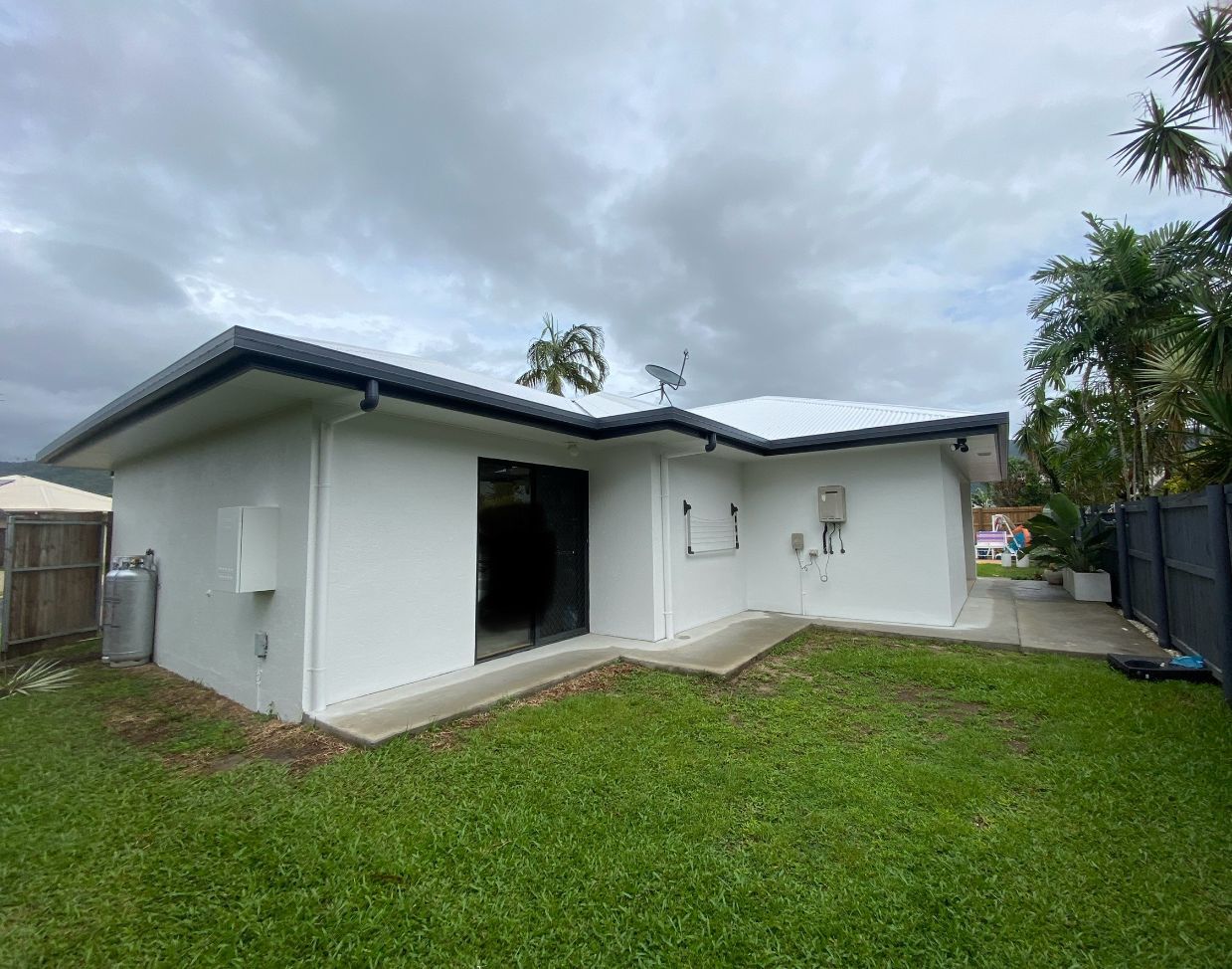 A Freshly Painted White House with A Green Backyard Lawn — Painting & Maintenance FNQ Handyman Service in Clifton Beach, QLD
