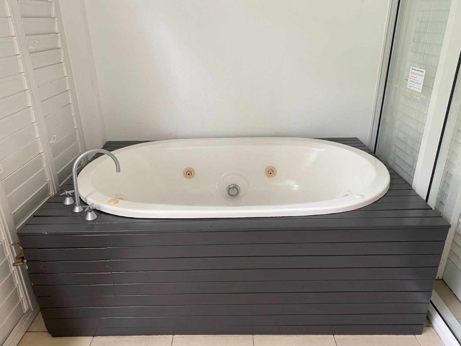 A Jacuzzi Tub is on Top of a Wooden Platform in a Bathroom — Painting & Maintenance FNQ Handyman Service in Clifton Beach, QLD