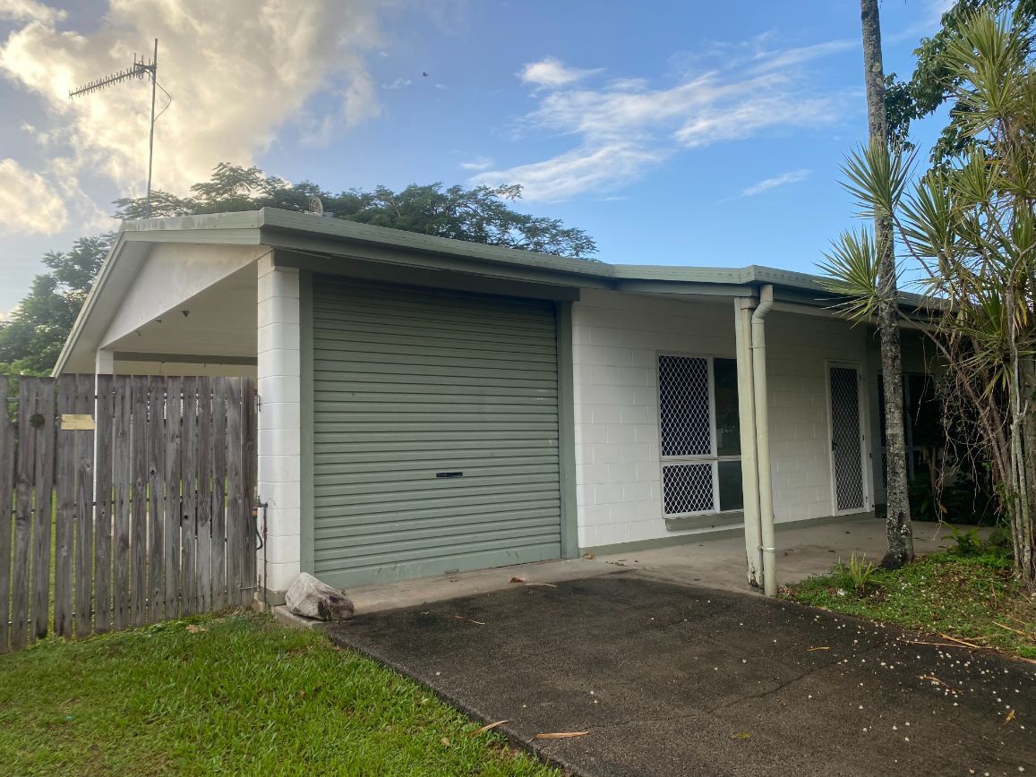 A Small White House With a Green Garage Door and a Wooden Fence — Painting & Maintenance FNQ Handyman Service in Clifton Beach, QLD