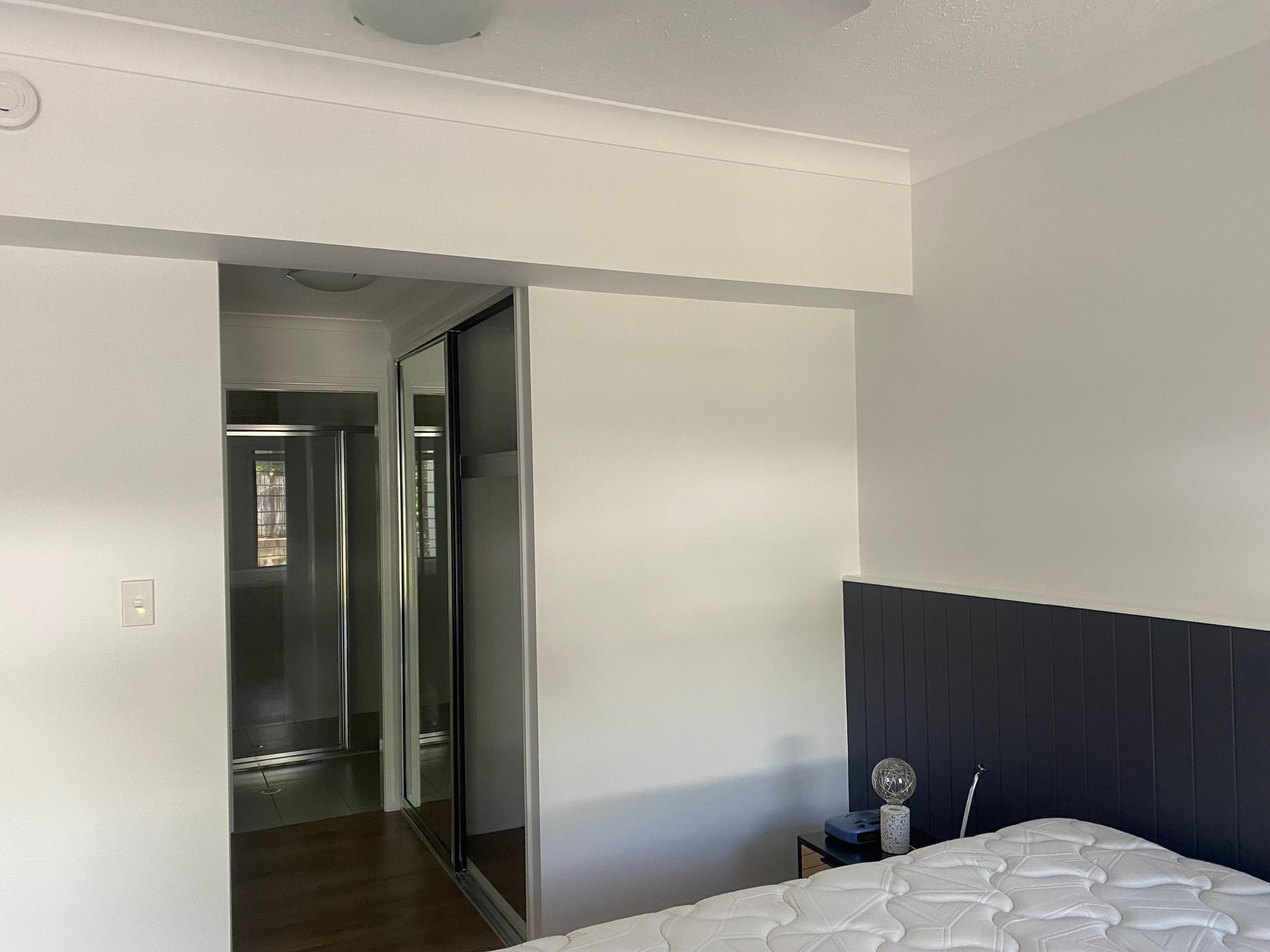 A Bedroom With a Bed and a Sliding Glass Door Leading to a Bathroom — Painting & Maintenance FNQ Handyman Service in Clifton Beach, QLD