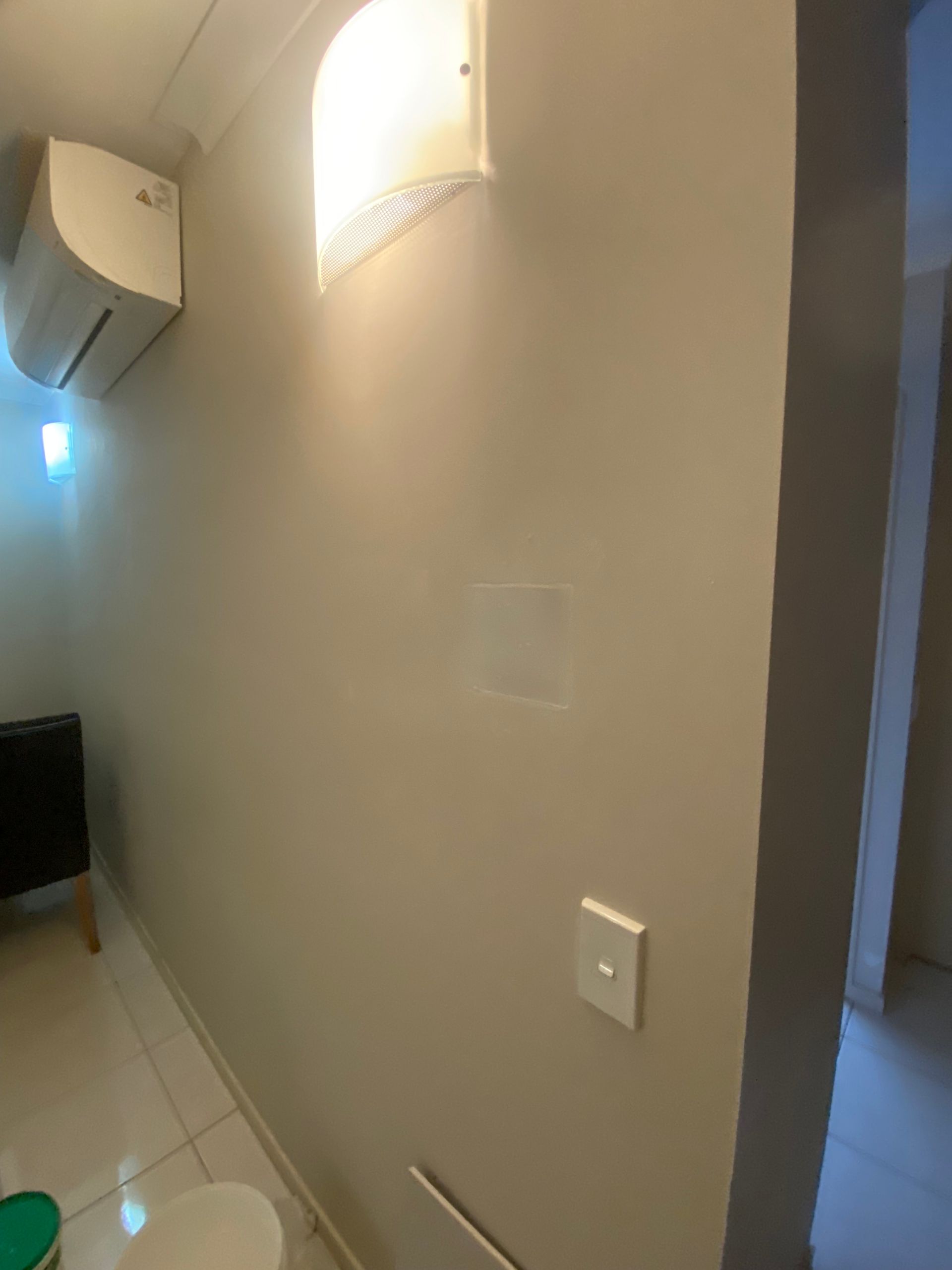 A bathroom with a toilet and a light on the wall — Painting & Maintenance FNQ Handyman Service in Clifton Beach, QLD