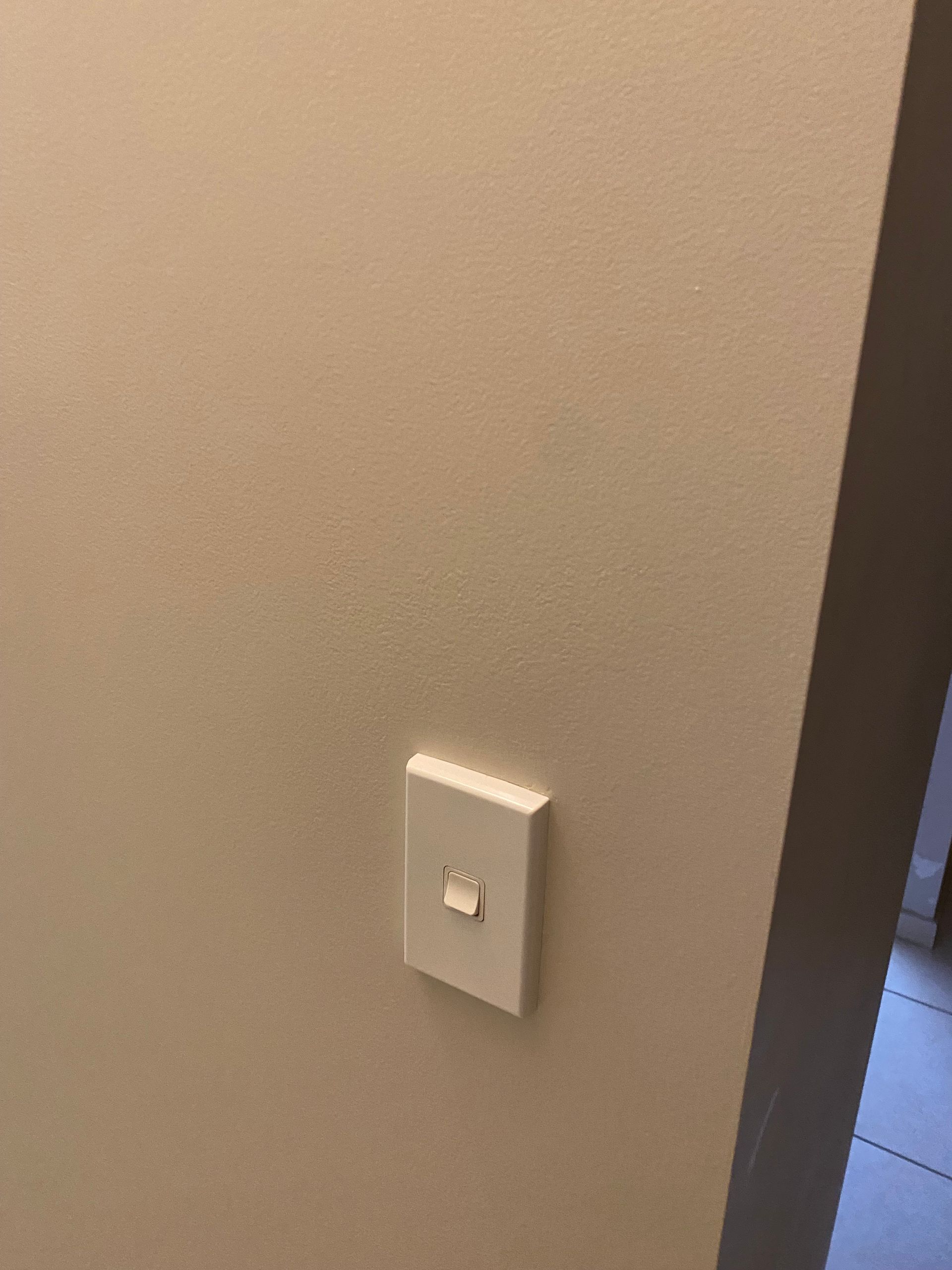 A white light switch is mounted on a beige wall — Painting & Maintenance FNQ Handyman Service in Clifton Beach, QLD