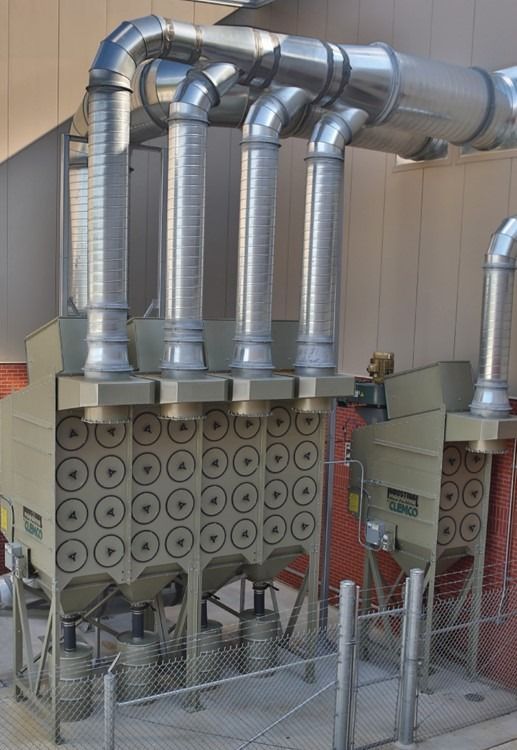 Industrial dust collector machines with metal hoppers, vents, and support frames in beige-gray finish