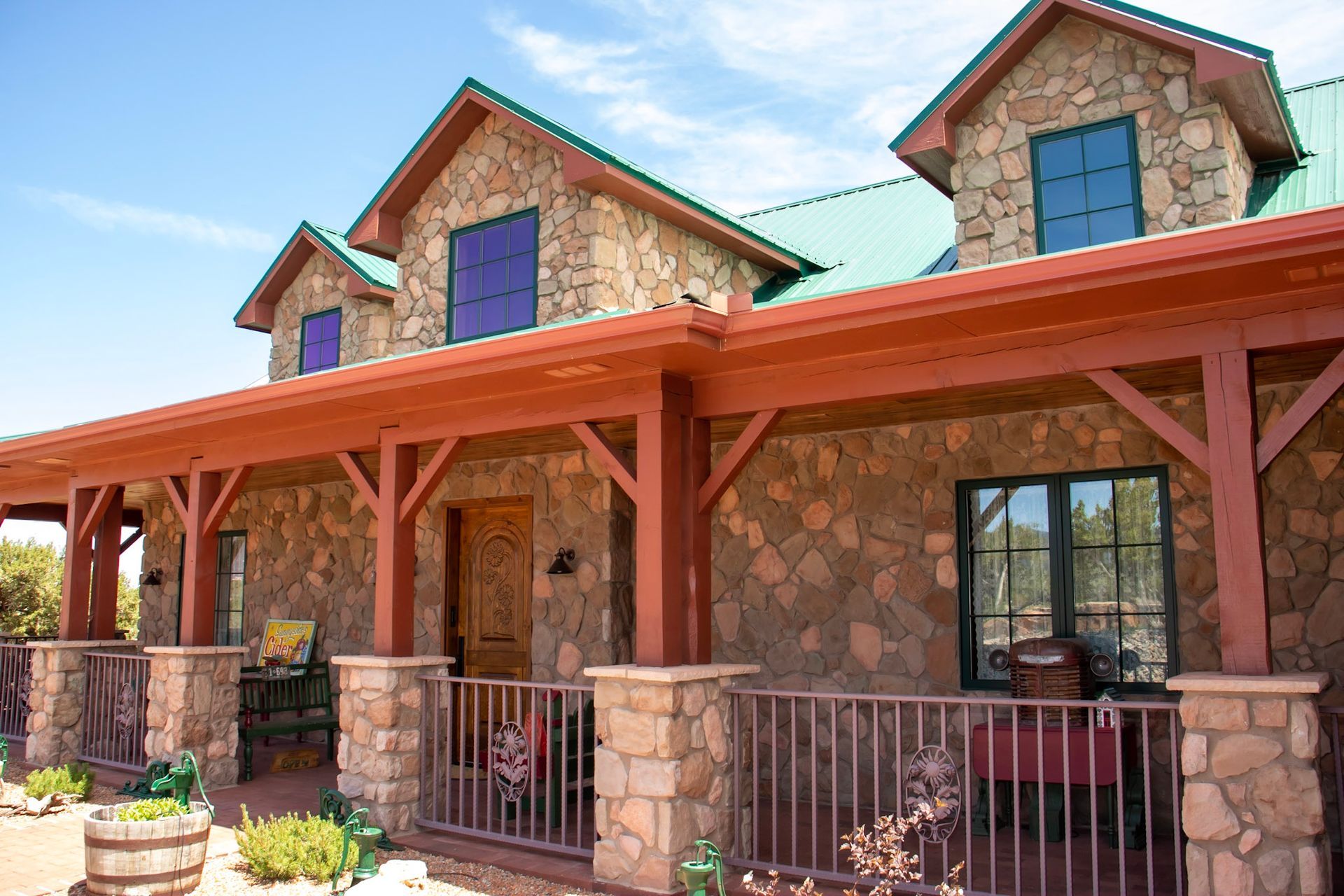 a large stone house with a porch and a green roof