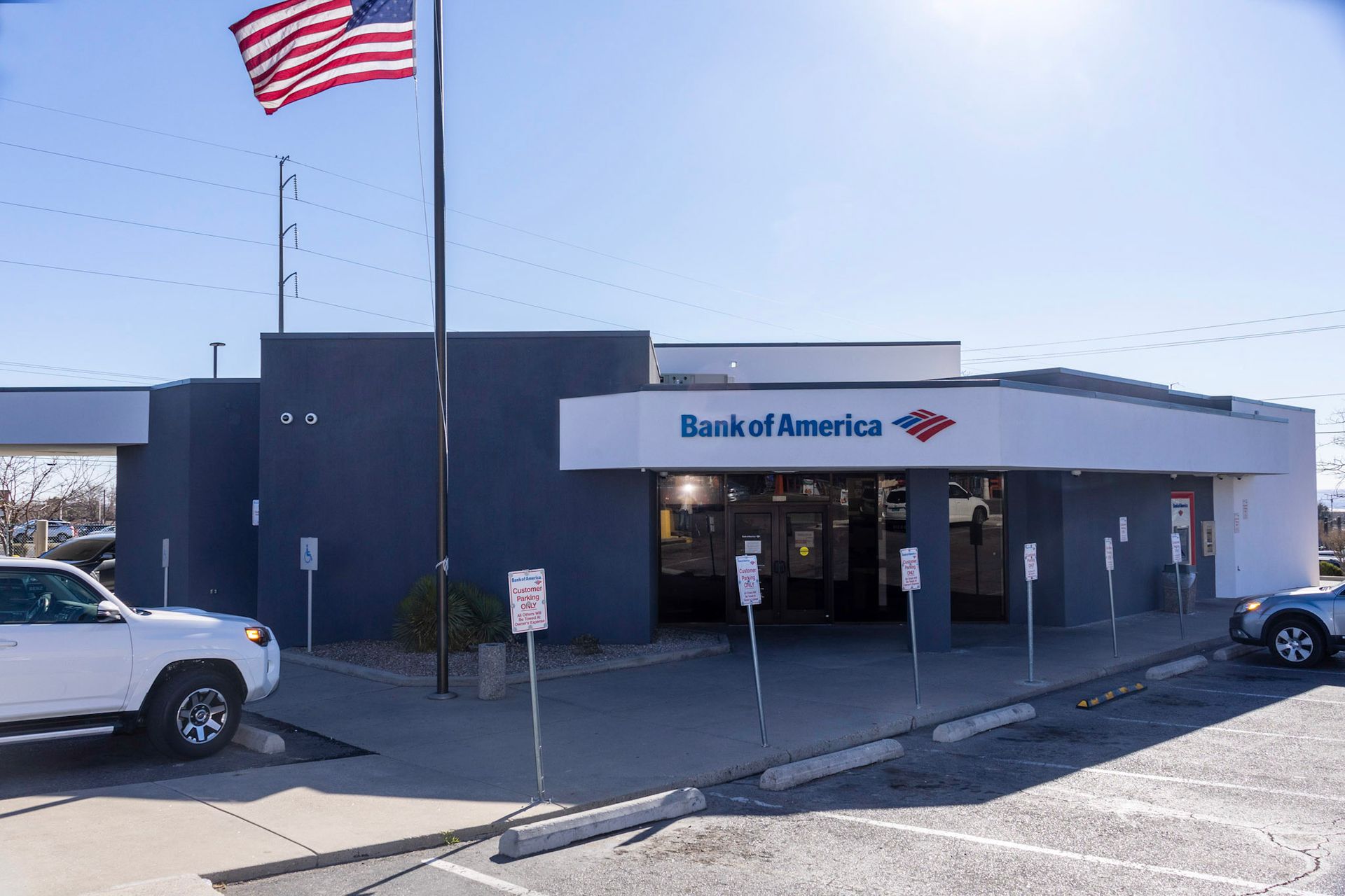 a white truck is parked in front of a bank of america branch .