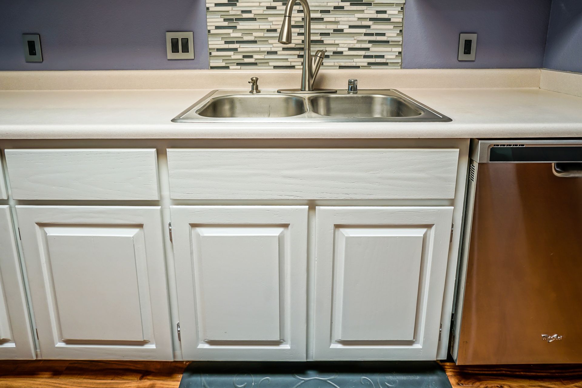 a kitchen with white cabinets , a stainless steel sink , and a stainless steel dishwasher .