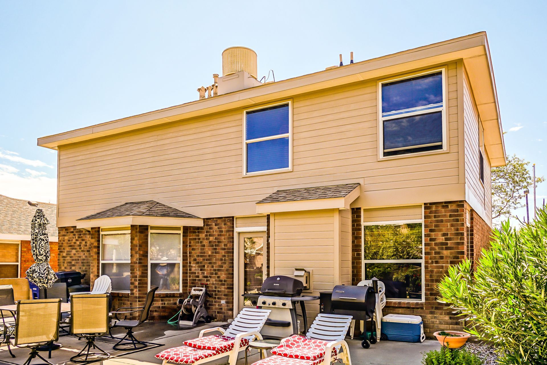 the backyard of a house with a patio and chairs and a grill .