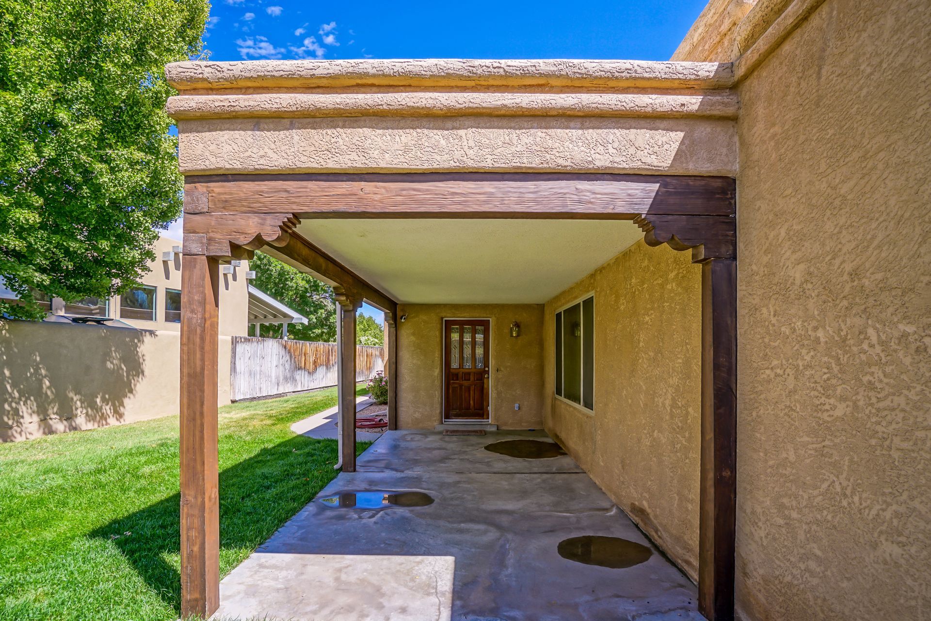 a covered patio with a wooden pergola on the side of a house .