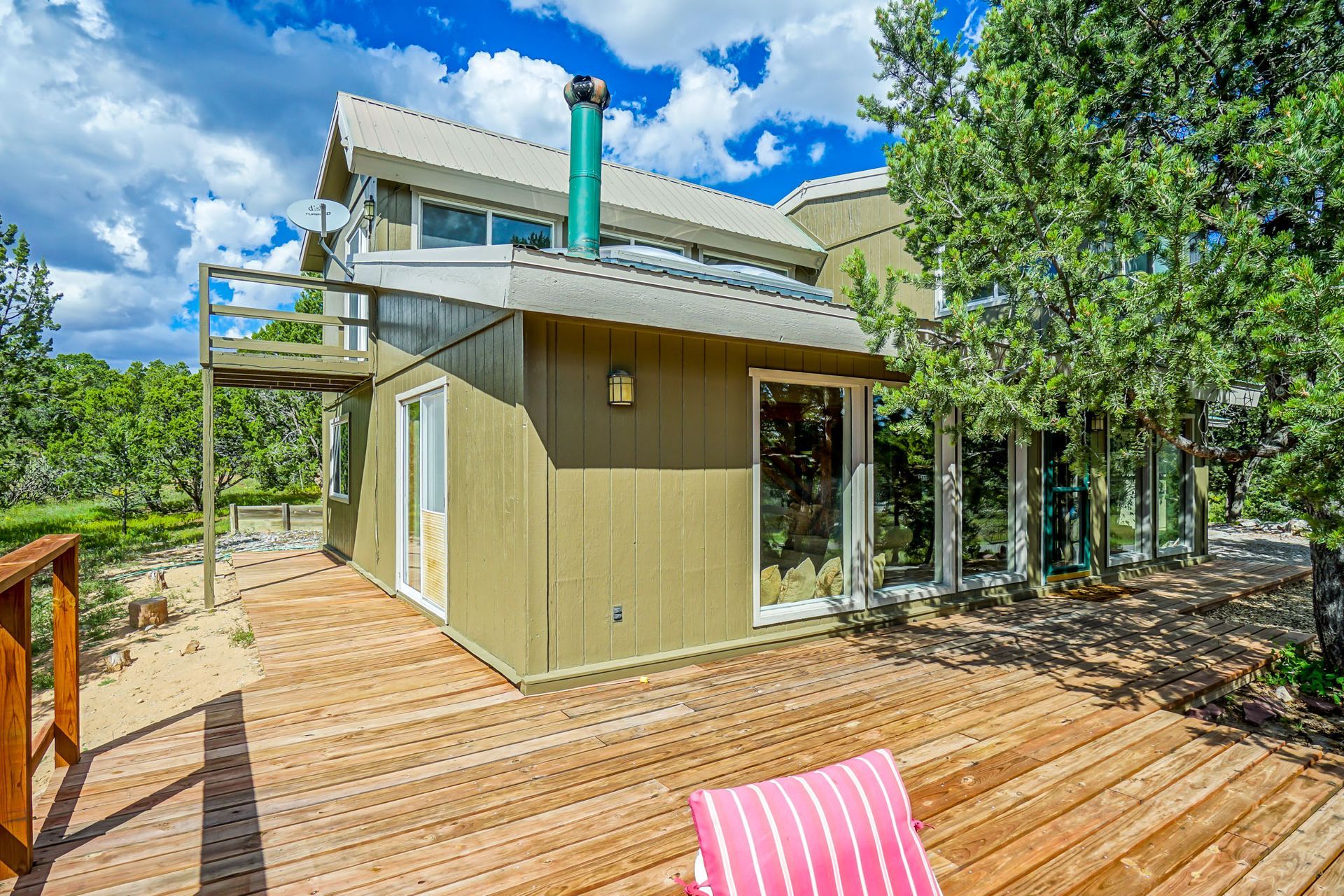 a house with a wooden deck and a pink chair in front of it .