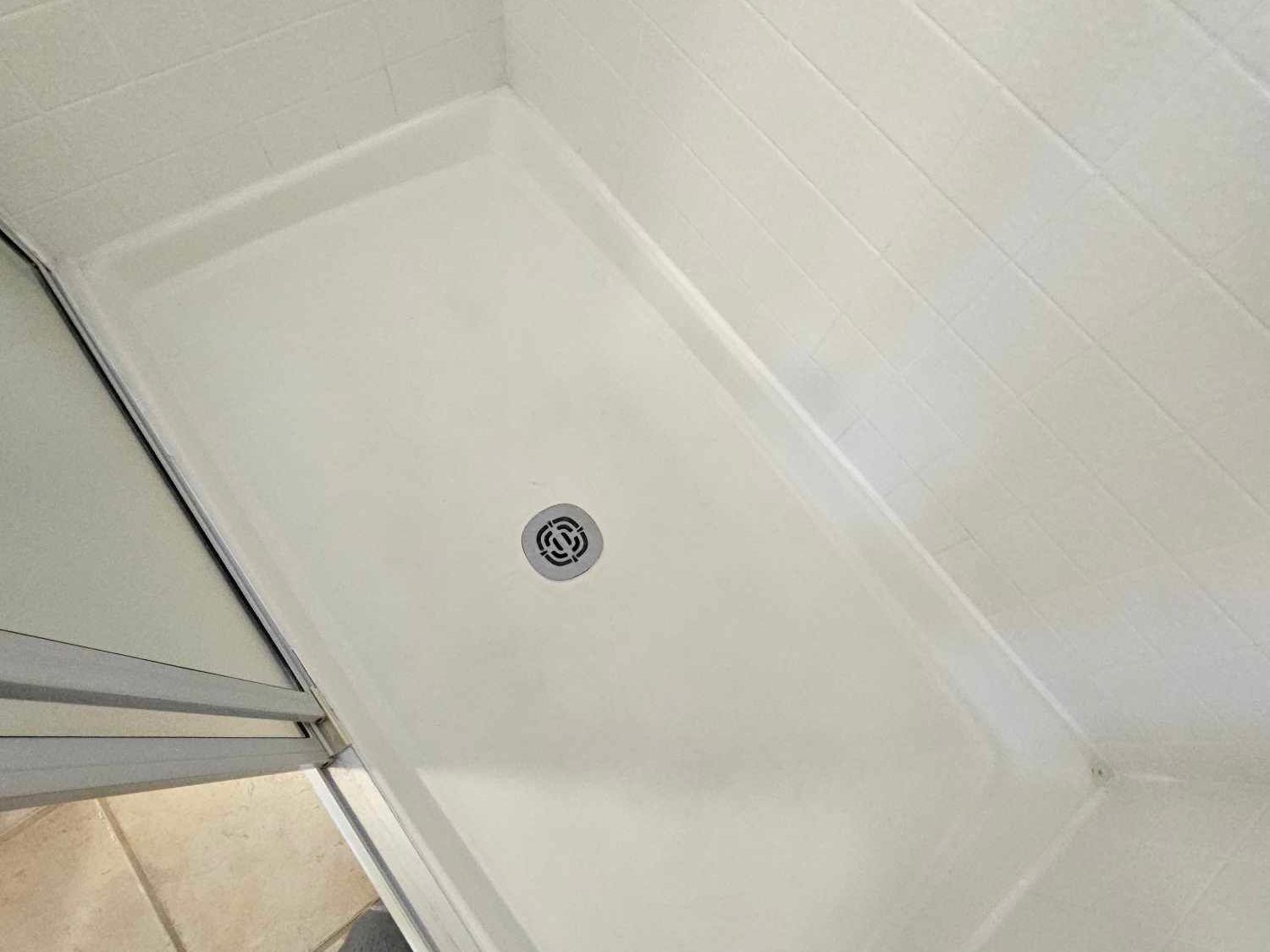 Image of a shower that has just been reglazed. You can see a shiny white shower floor with glass sliding door to the left.
