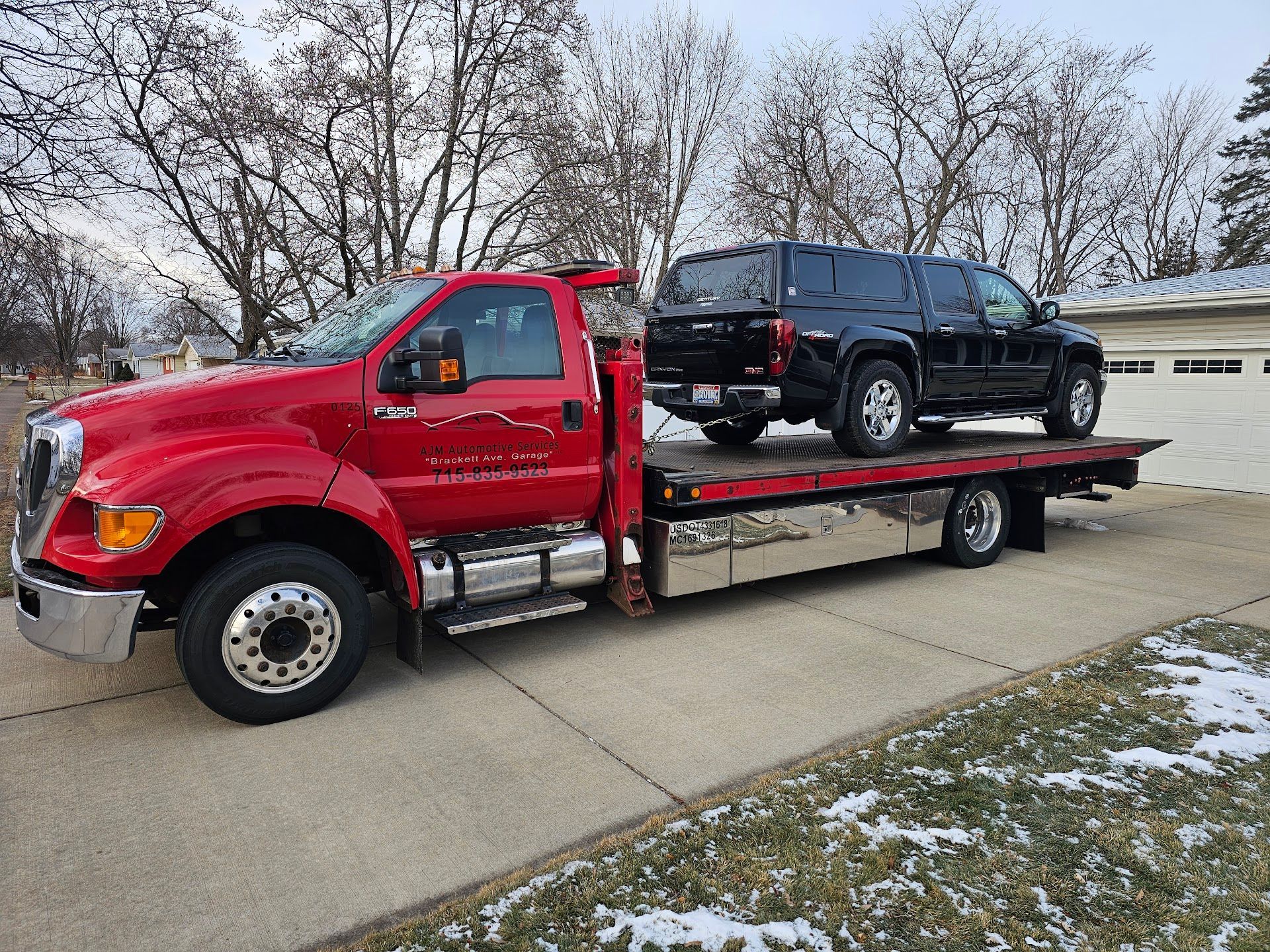 Red Flatbed Tow Truck Hauling Pickup Truck In Eau Claire | AJM Automotive Services LLC