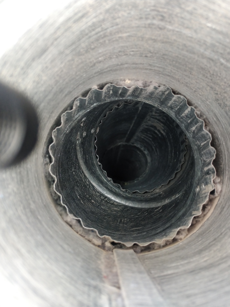 View inside a corrugated metal pipe, possibly a vent, with dirt and debris visible.