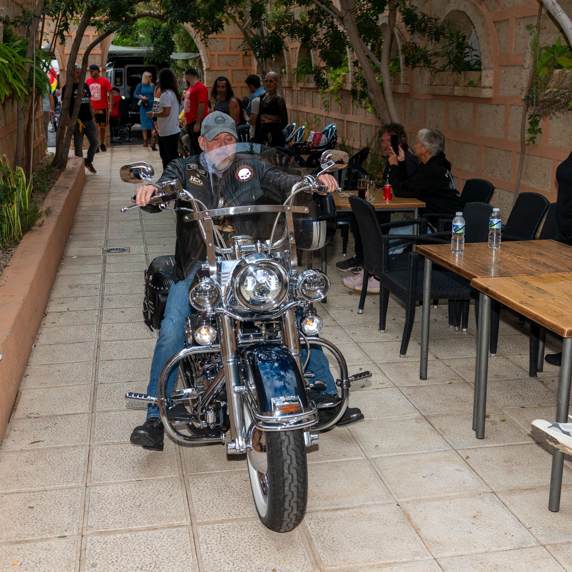 A man wearing a mask is riding a motorcycle down a sidewalk