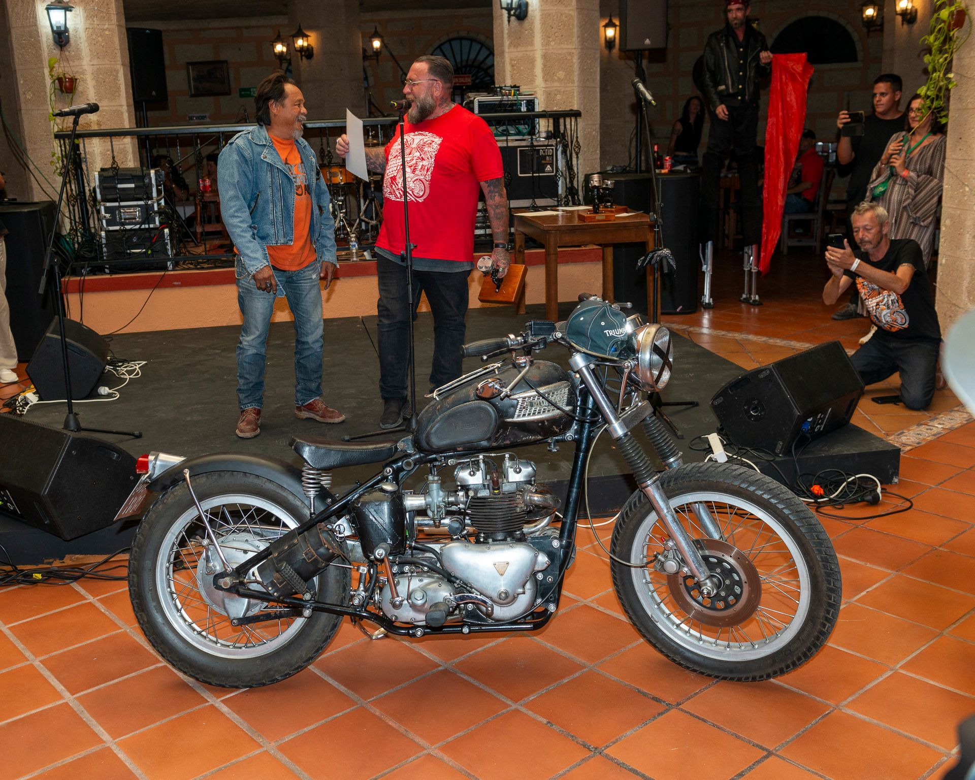 A man in a red shirt stands next to a motorcycle