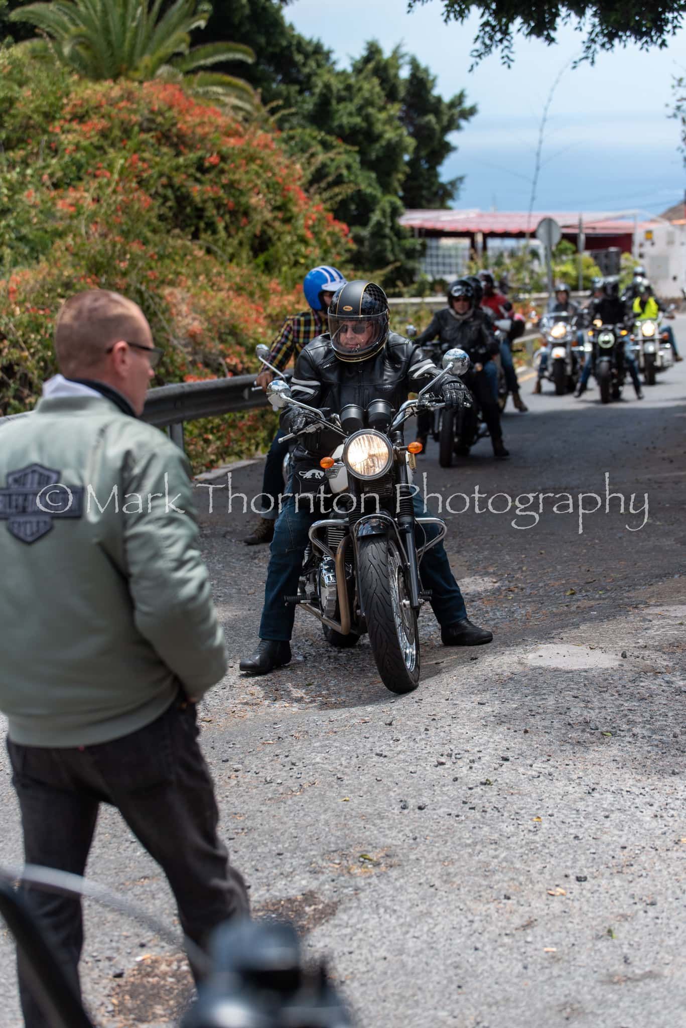 A man in a harley davidson jacket stands in front of a group of motorcycles.