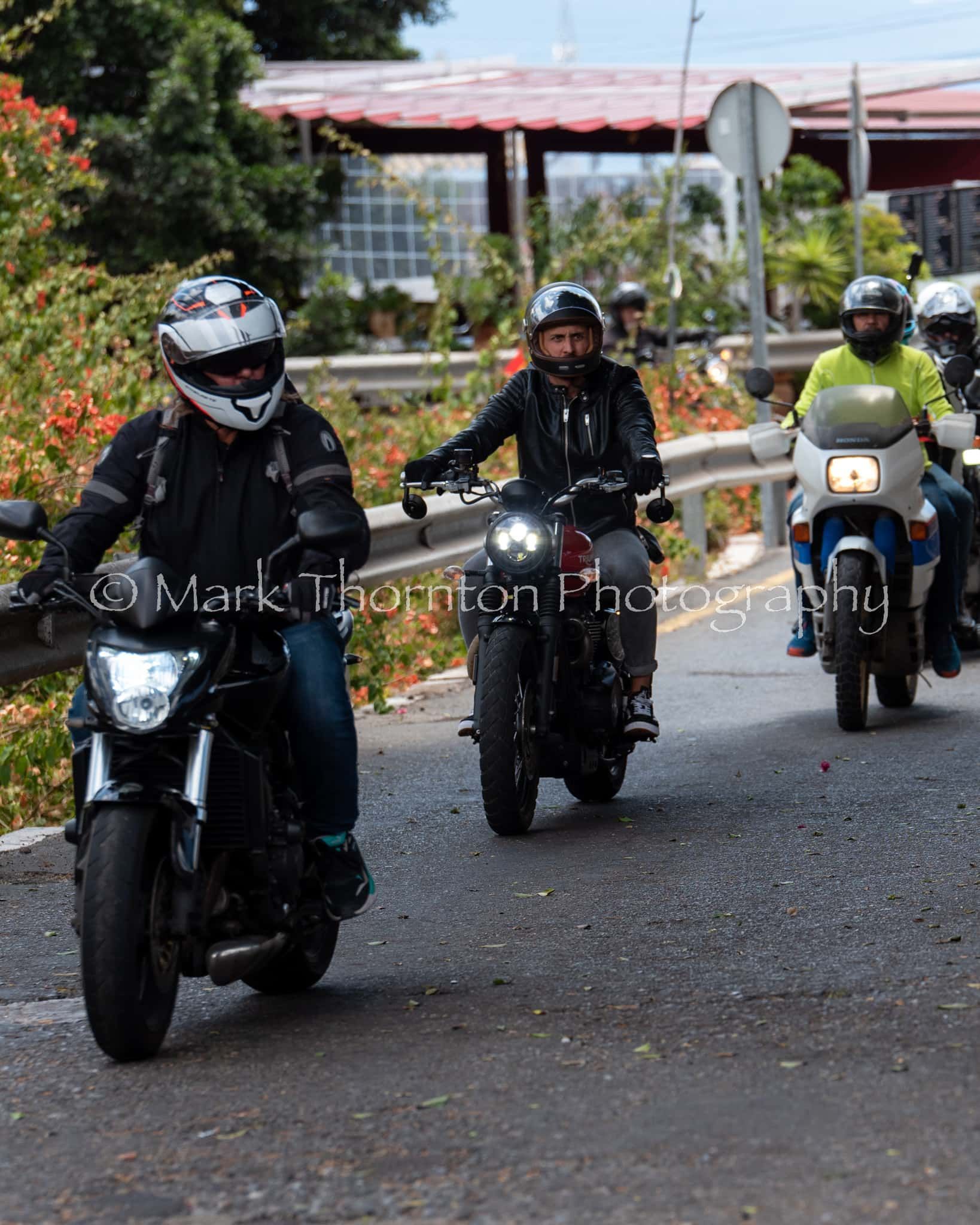A group of people are riding motorcycles down a road