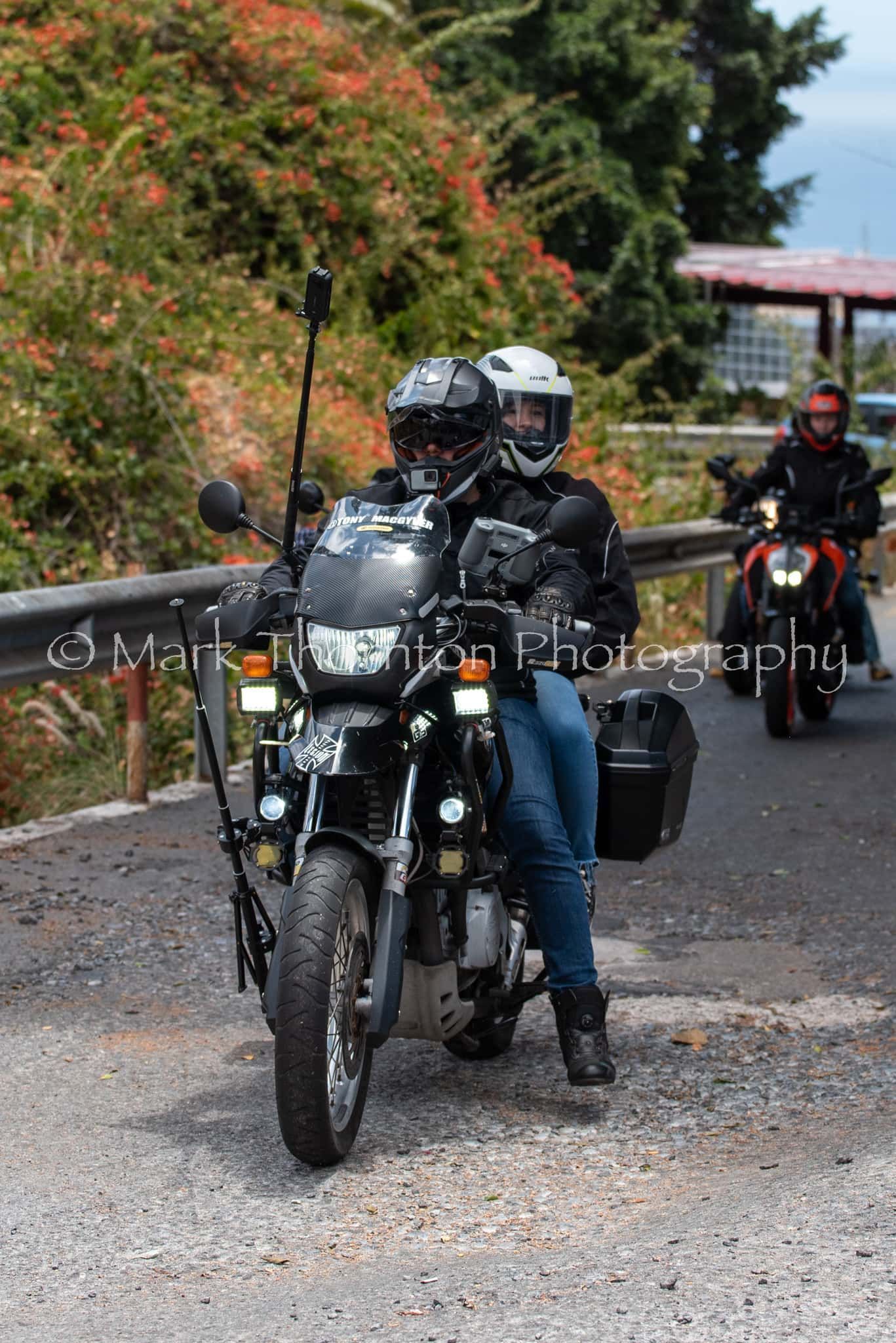 A couple of people are riding motorcycles down a road.