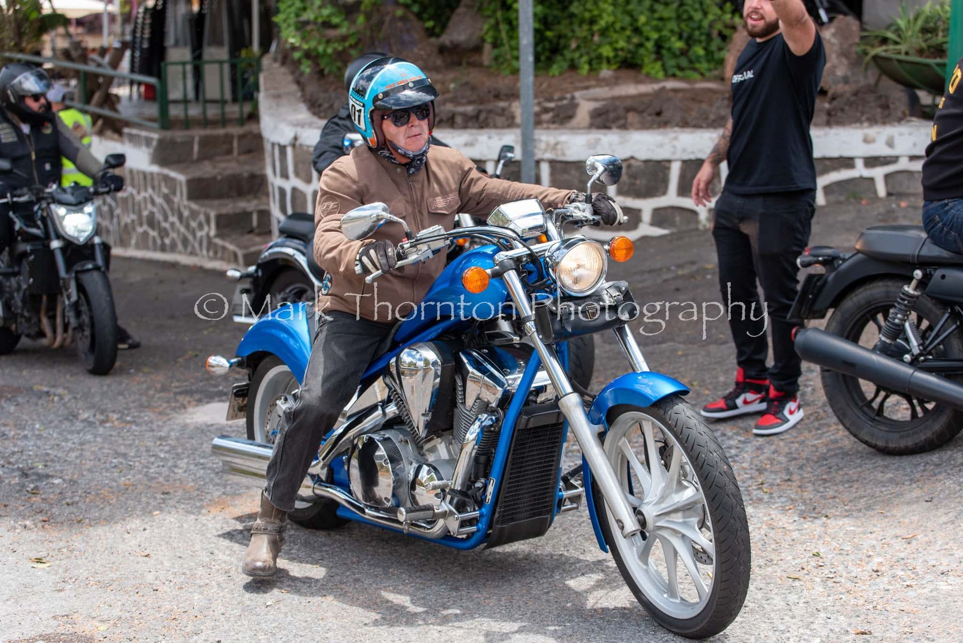 A man is riding a blue motorcycle on a street.