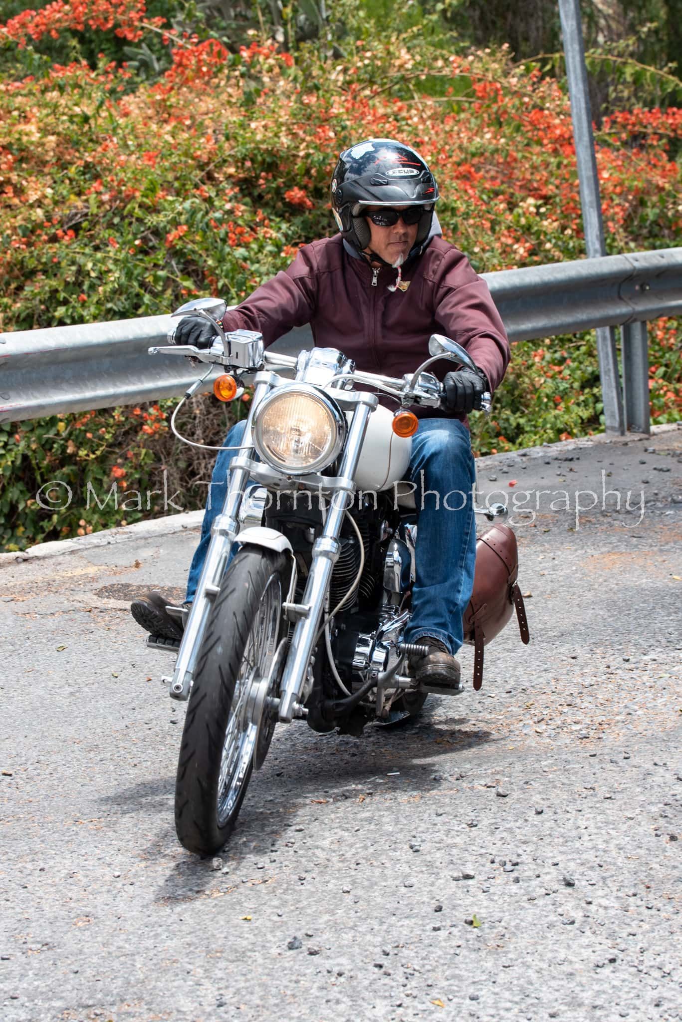 A man is riding a motorcycle down a road.