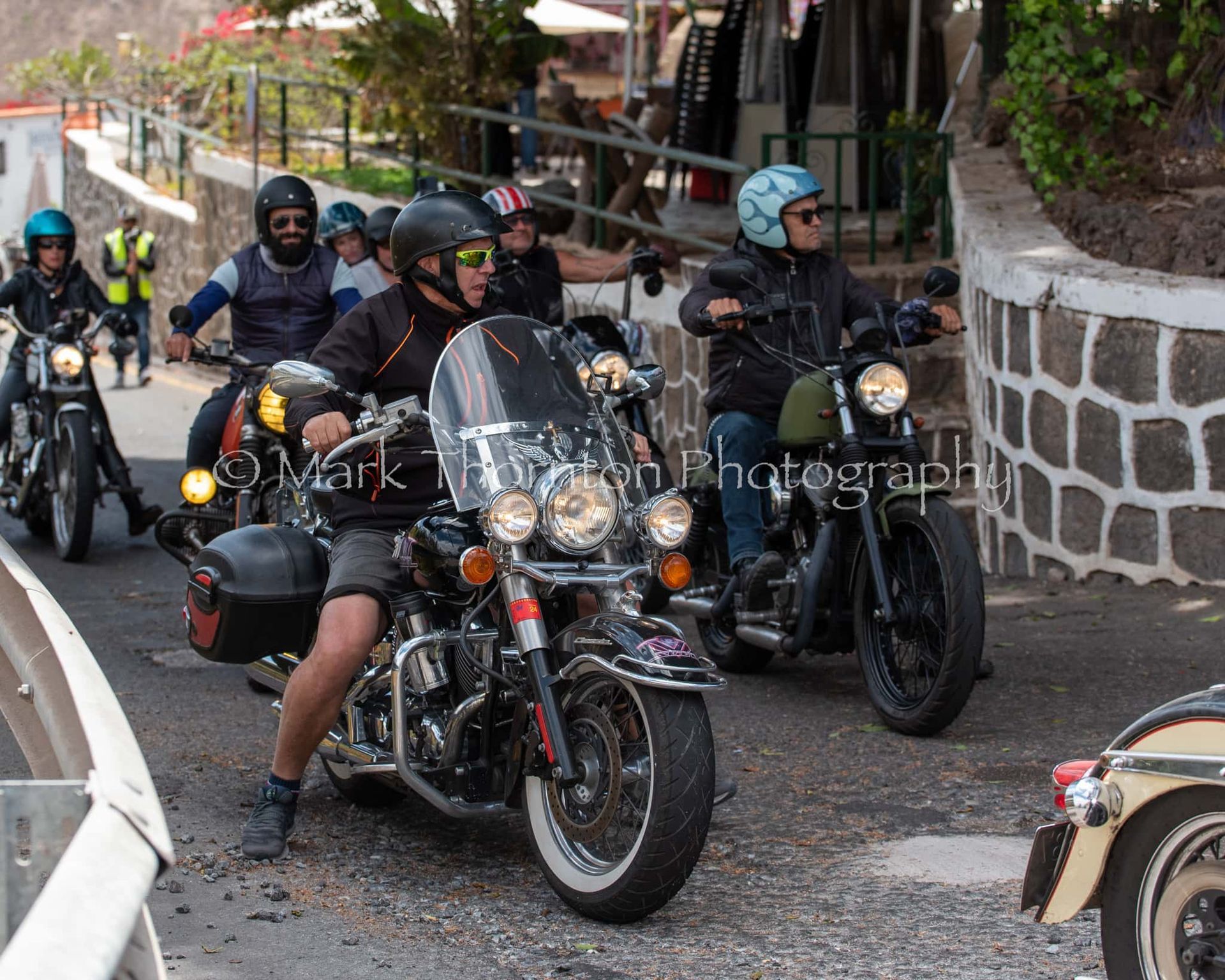 A group of men are riding motorcycles down a street