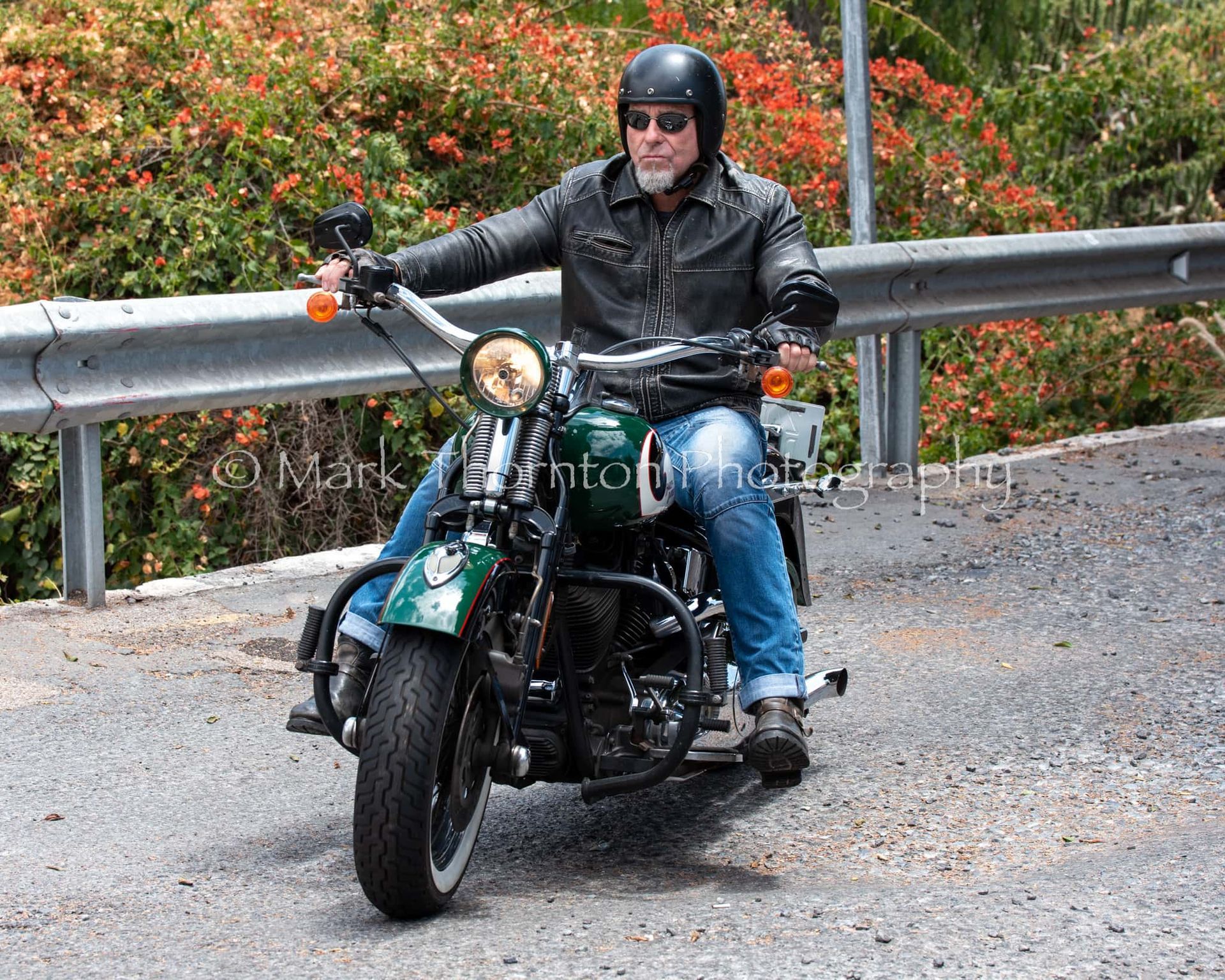 A man is riding a green motorcycle on a road