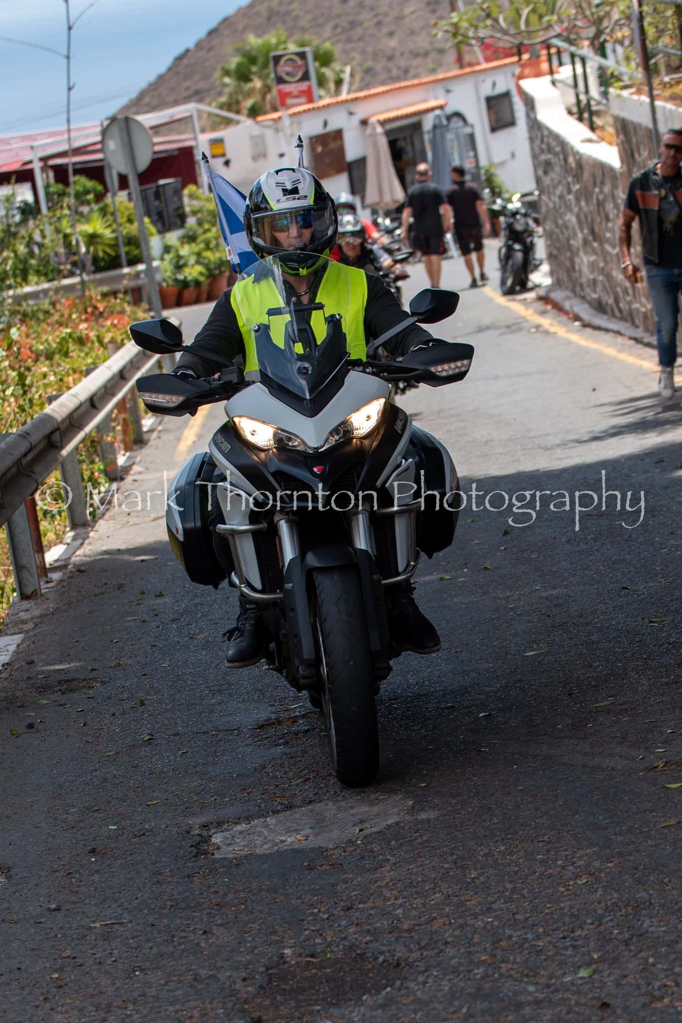 A man is riding a motorcycle down a road with the word photography on the bottom