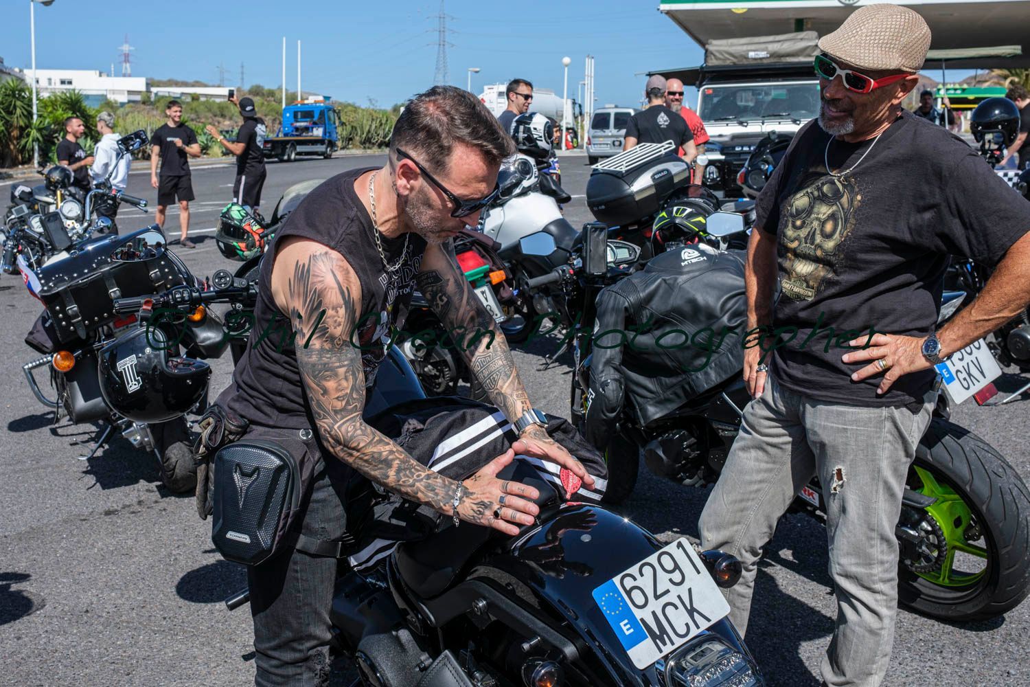 Two men are standing next to a motorcycle in a parking lot.