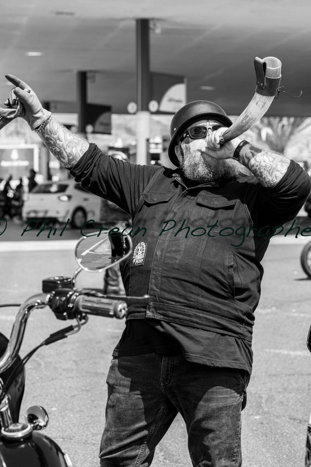 A man wearing a helmet and sunglasses is riding a motorcycle and singing into a microphone.