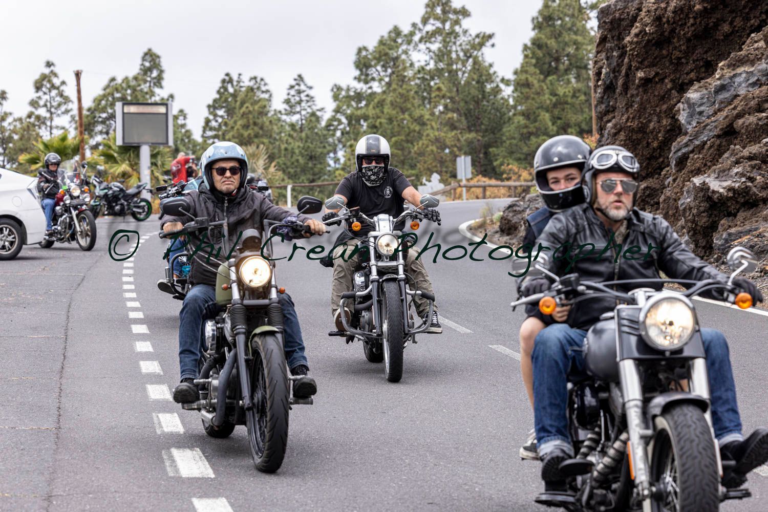 A group of men are riding motorcycles down a road.