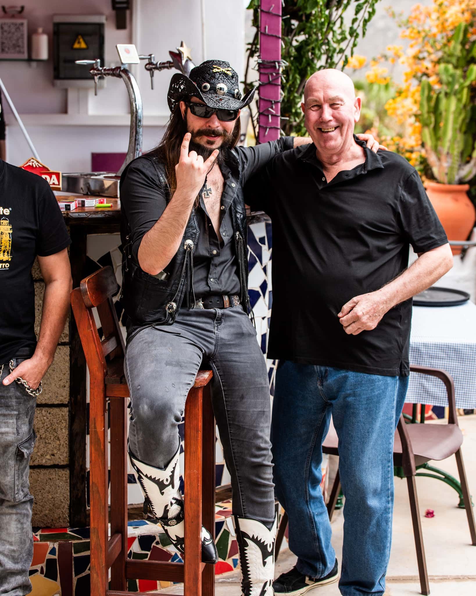 A man with long hair is sitting on a bar stool