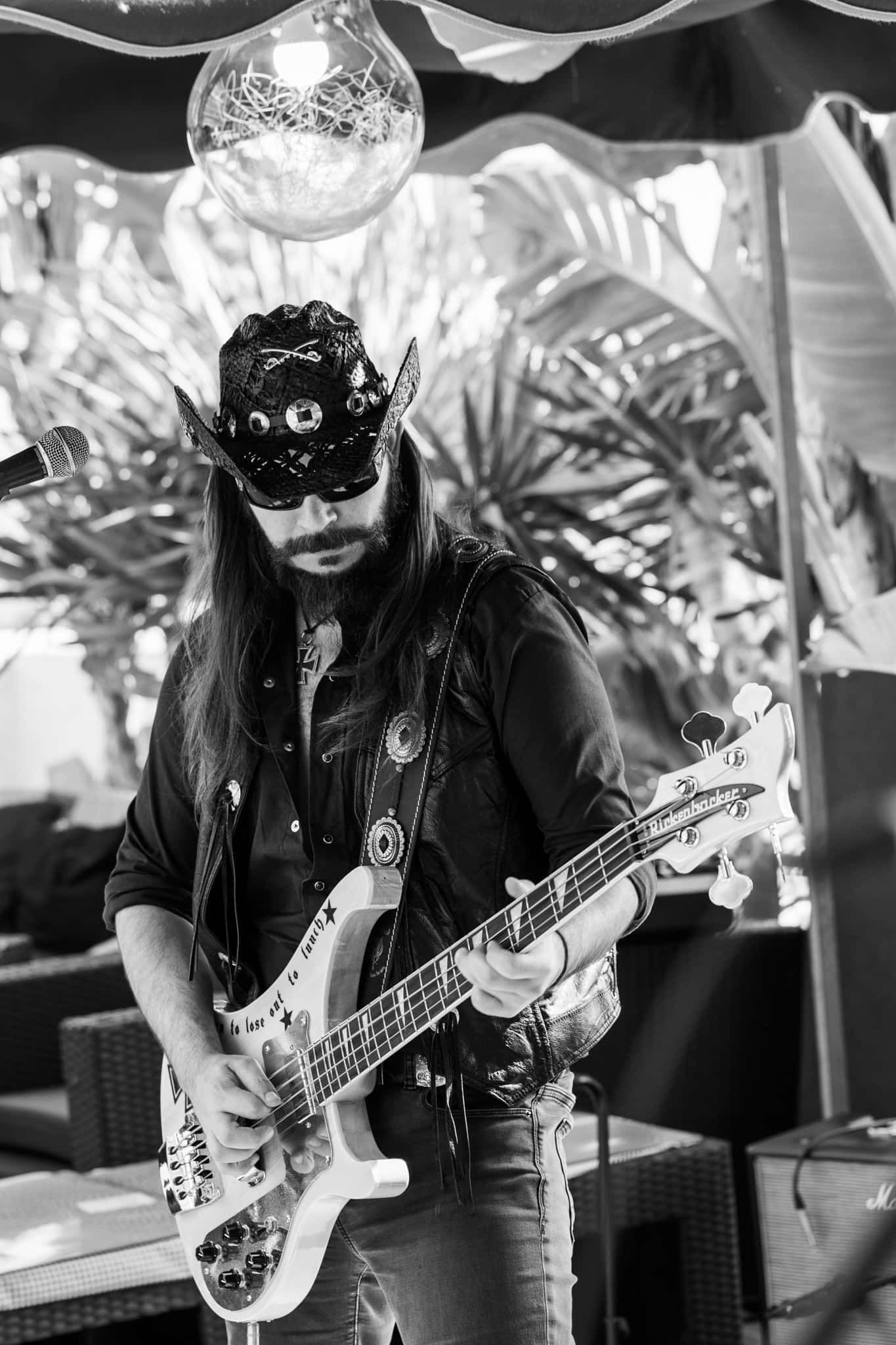 A man with long hair is playing a guitar in a black and white photo.