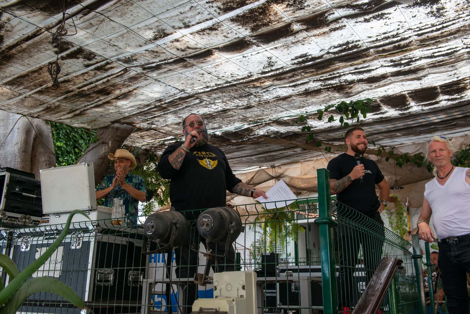 A man is sitting on a stage talking into a microphone.