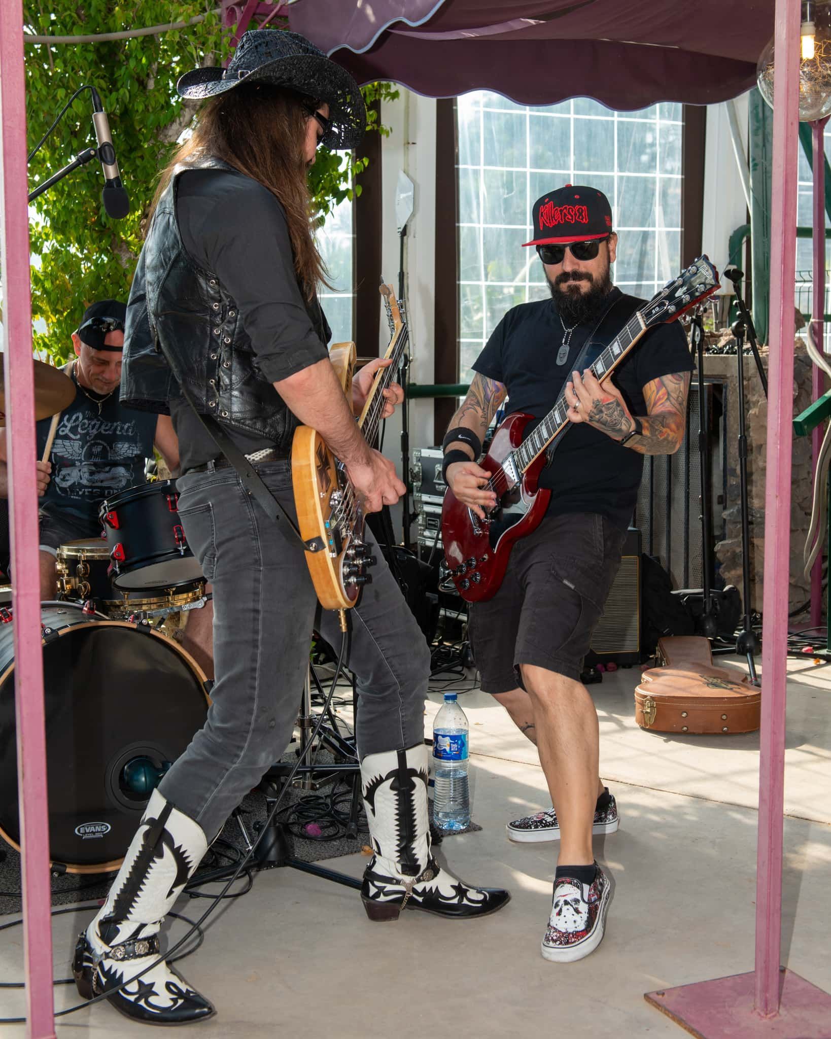 Two men are playing guitars in front of a drum set