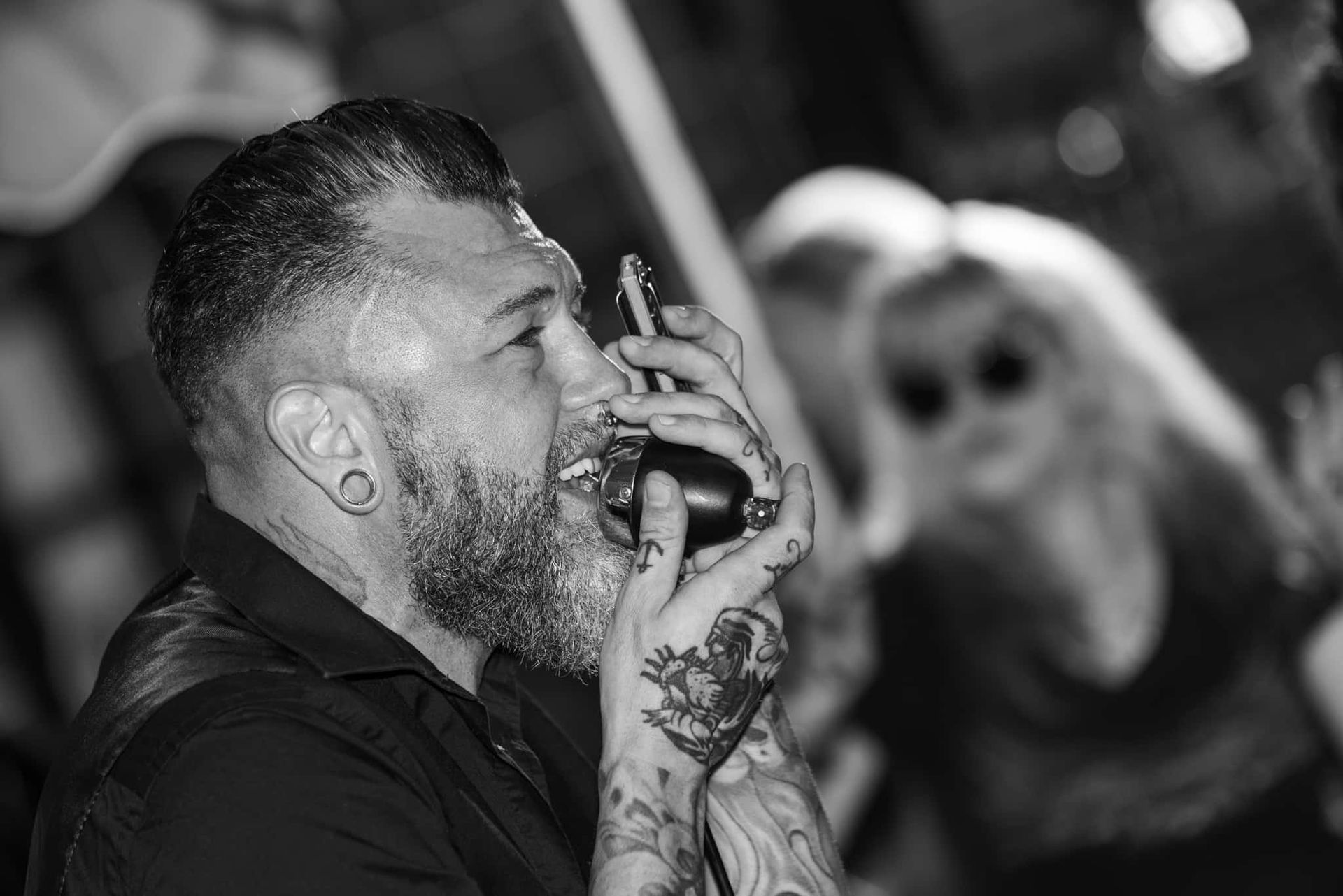 A man with a beard is singing into a microphone in a black and white photo.