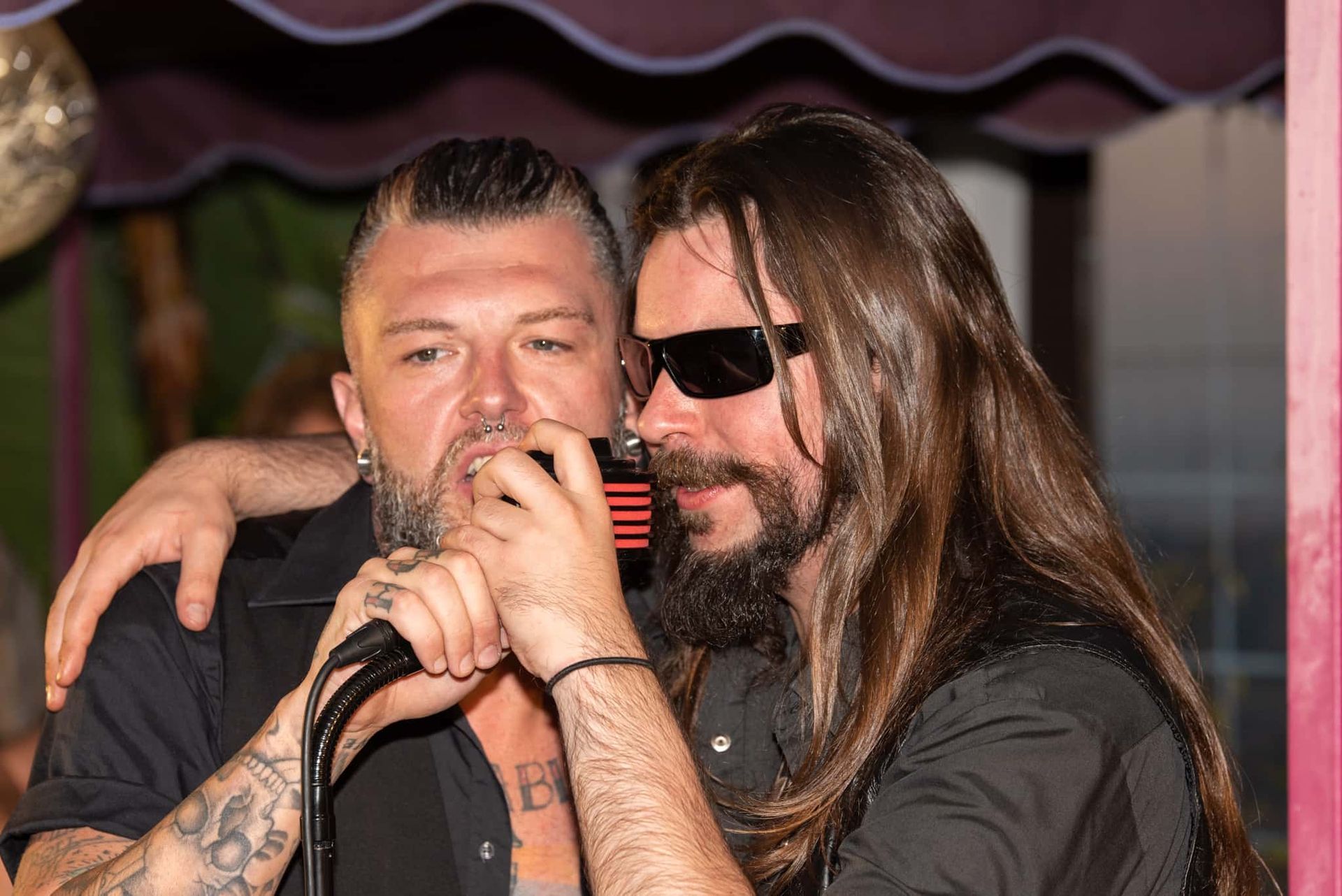 A man with long hair is singing into a microphone