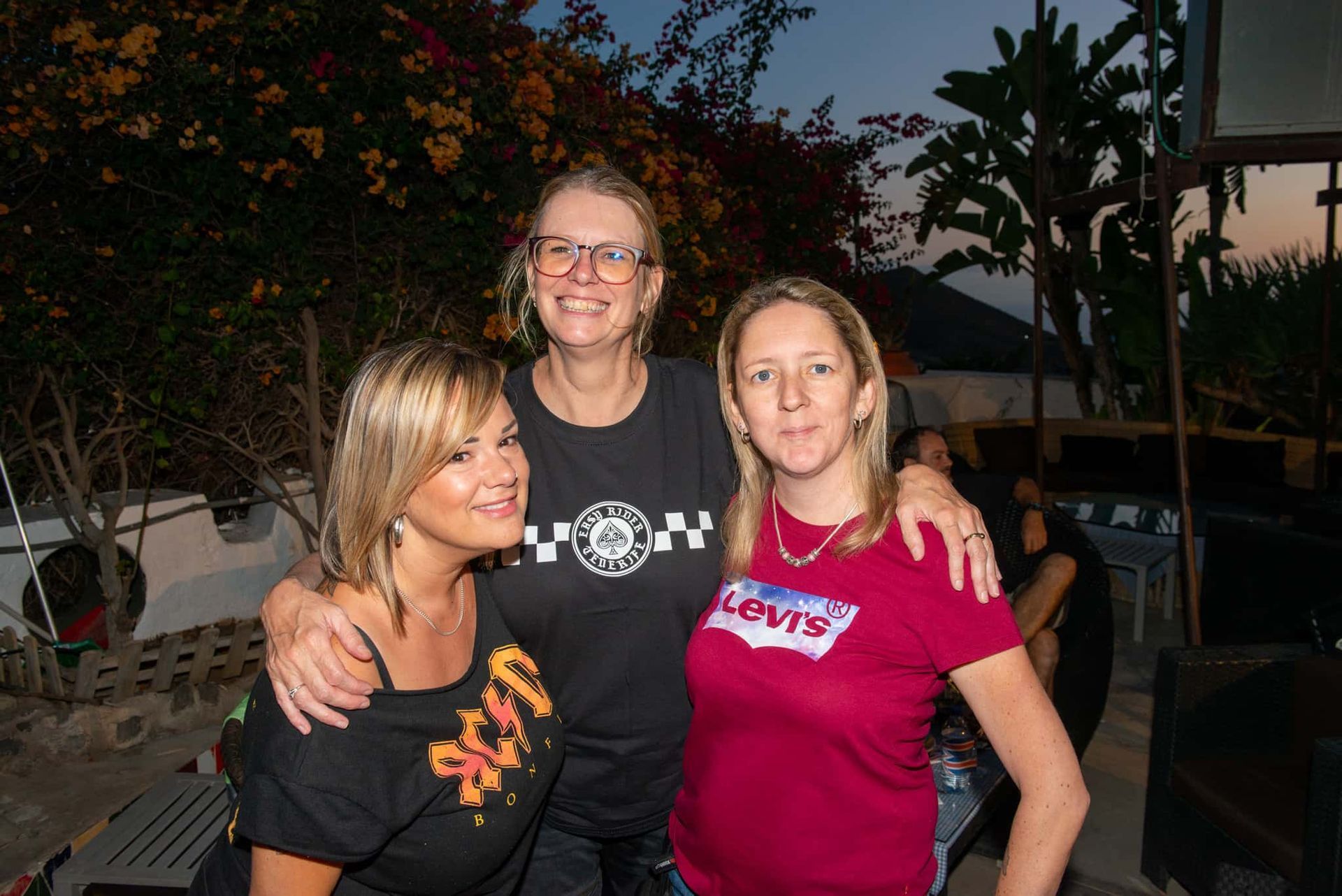 Three women posing for a picture with one wearing a levis shirt