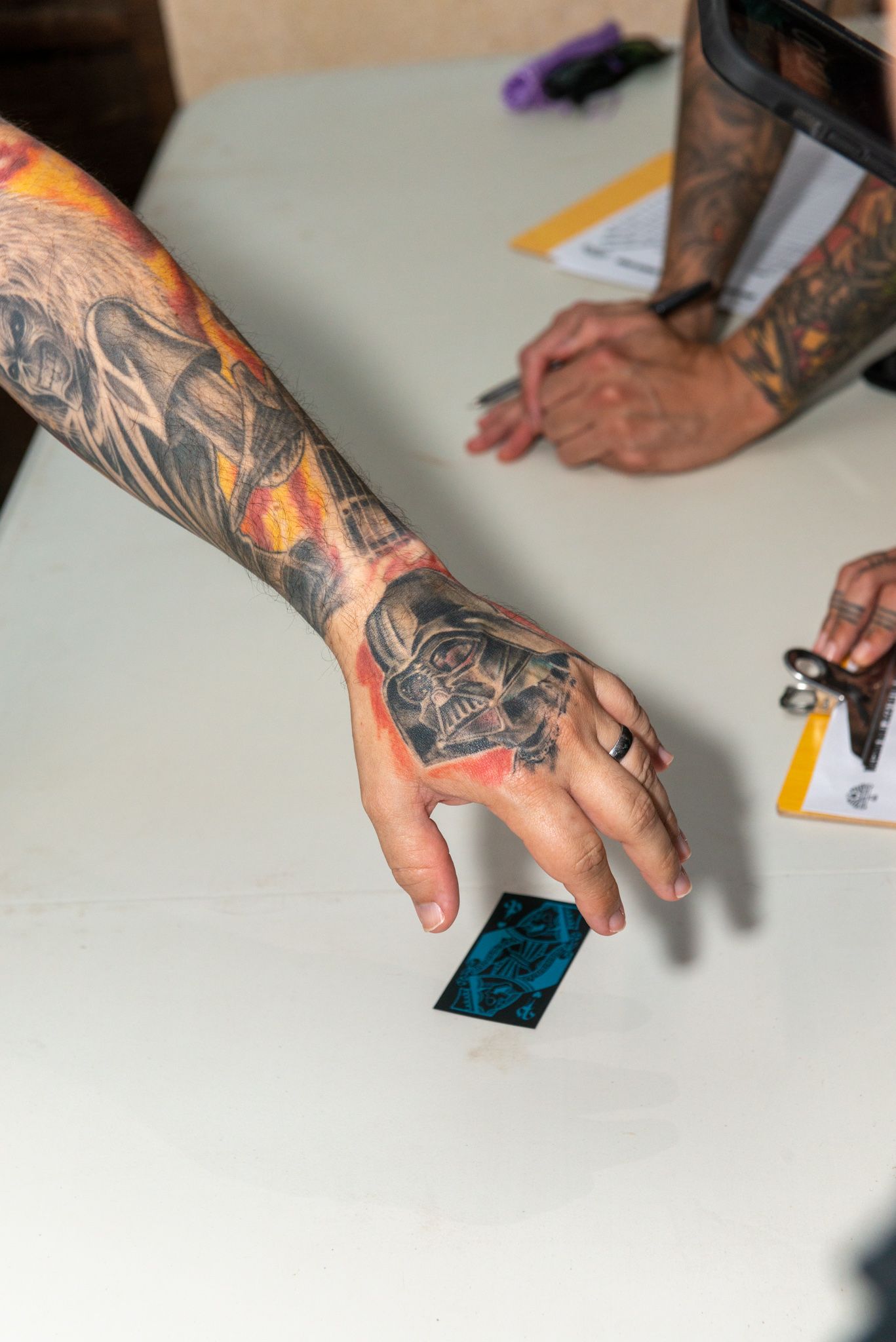 A person with a tattoo on their arm is holding a piece of paper.