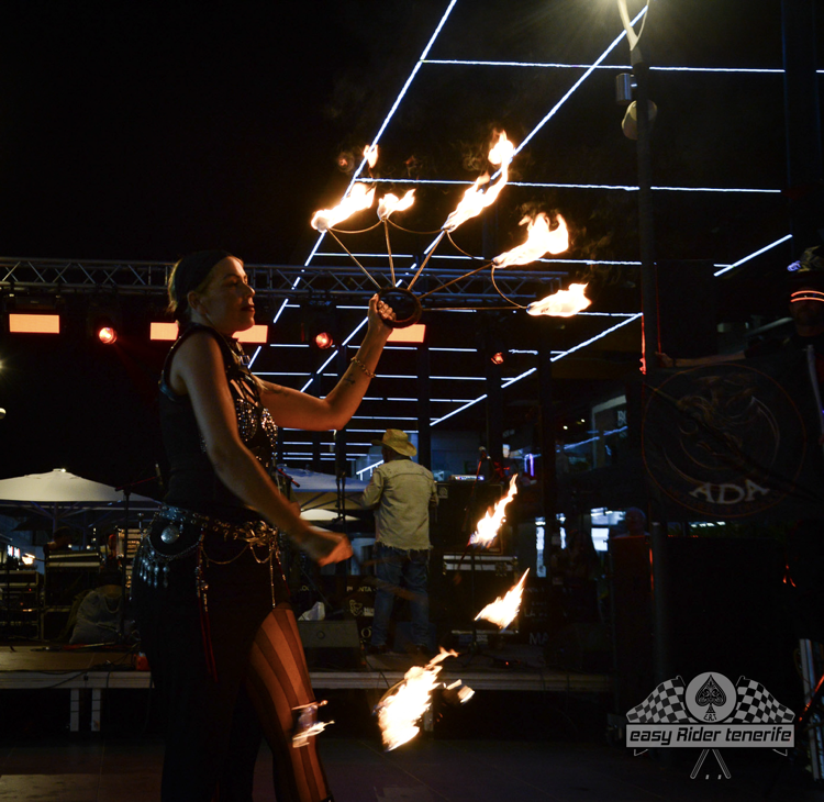 A woman is holding a stick of fire in front of a sign that says ' aida ' on it