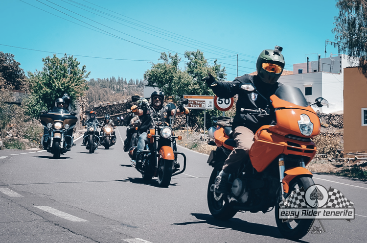 A group of motorcycle riders are riding down a road