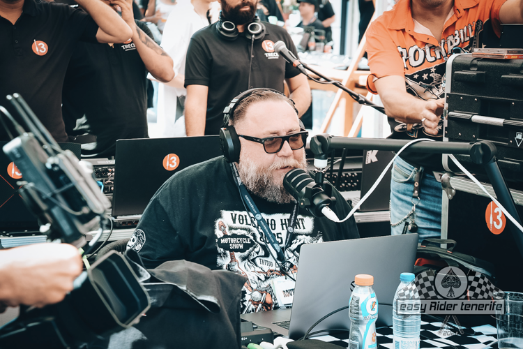 A man with a beard is sitting in front of a microphone.
