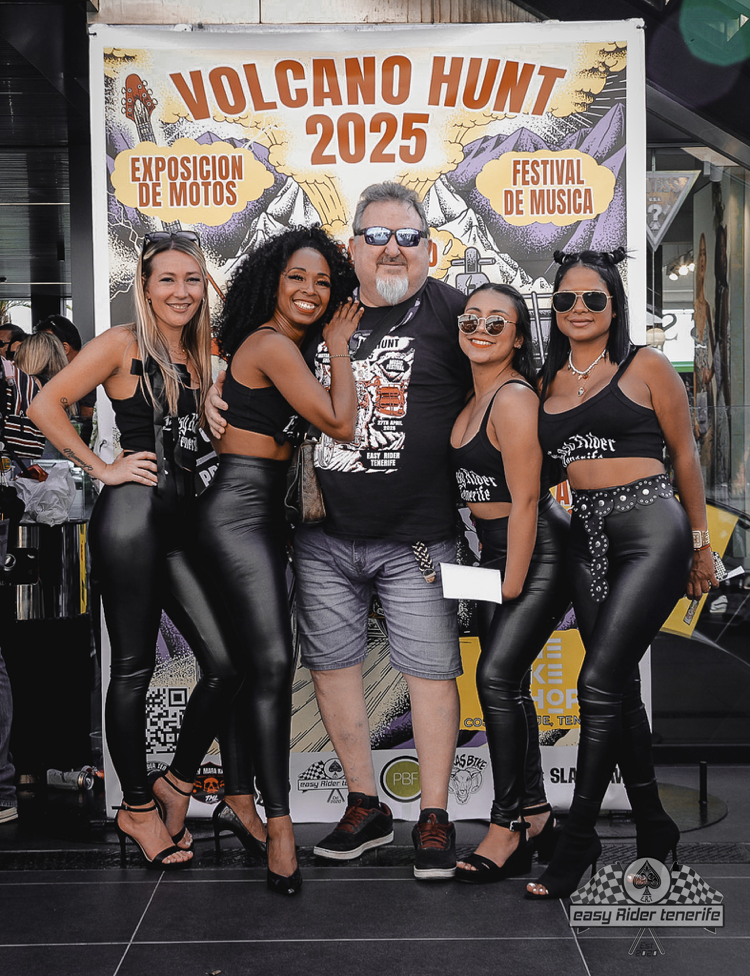 Man posing with five women in front of a banner for 