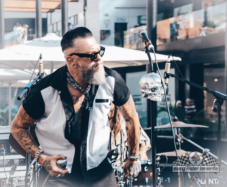 A man with a beard is standing in front of a microphone.