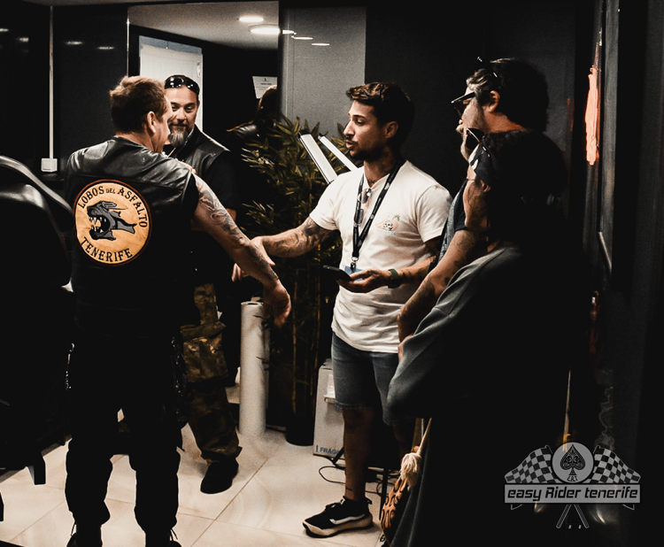 A group of men are standing in a room and one of them has a patch on his back that says ' motorcycle club '