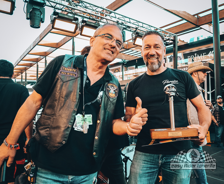 Two men are posing for a picture and one is holding a trophy